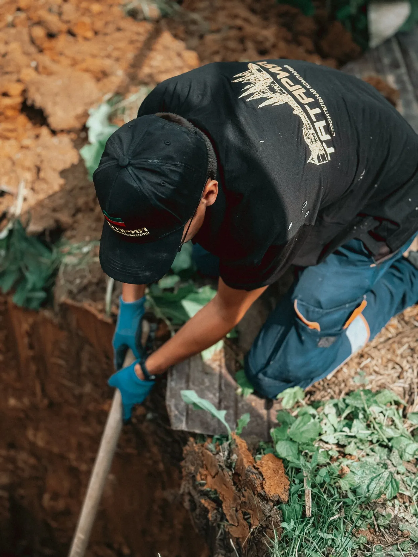 Technician hand-digging a trench to reach a buried tank lid